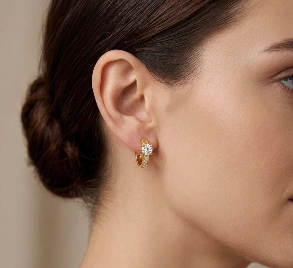 close-up of a woman wearing gold hoop earrings with a diamond accent.
